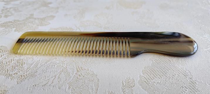 A short pocket comb with a striated/marbled appearance, ranging from beige to light brown to black.